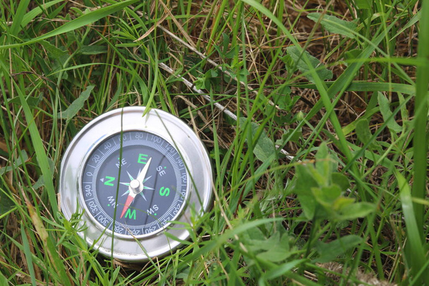 круглый компас на фоне летней травы как символ туризма с компасом, путешествия с компасом и активного отдыха с компасом - Фото, изображение