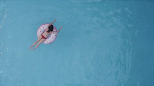 Egyedül fiatal nő diák lánya hűtés pihentető úszás lebegő felfújható cső kör rózsaszín fánk körül kék medence nyári üdülőhely party ünneplés külföldön, teljes hosszúságú lövés - Felvétel, videó