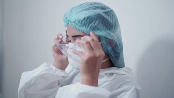 Beyaz elbise giyen Asyalı kadın hemşire, koruyucu giysi, koruyucu gözlük, n95 maske ve yüz kalkanı salgını Corona virüsü, tıp kliniğinde, bulaşıcı hastalıkların önlenmesi  - Video, Çekim