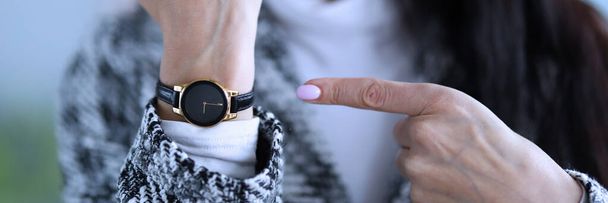 Δυσαρεστημένη γυναίκα δείχνει χρόνο στο ρολόι της. - Φωτογραφία, εικόνα