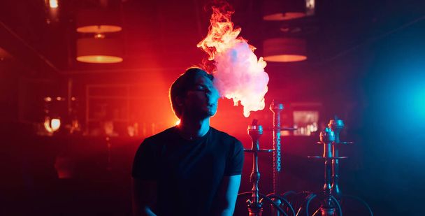 mladý muž kouří shisha a vypustí oblak kouře - Fotografie, Obrázek