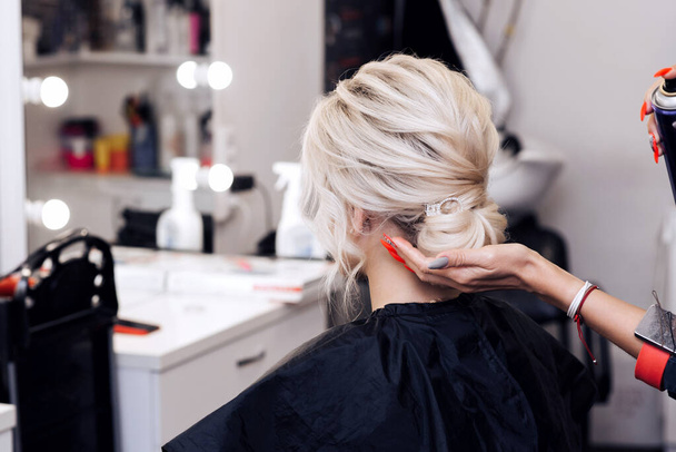 mains d'un coiffeur faire une coiffure pour une fille blonde - Photo, image