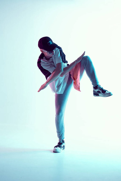 Guy dancing contemporary dance in studio. Neon light blue background. Acrobatic bboy dancer. Break dance lessons. - Фото, зображення