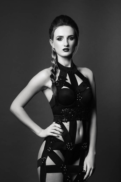 white girl model on a dark background in a dress made of cut stripes of black fabric - Foto, Imagen
