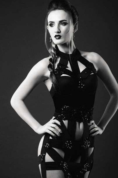 white girl model on a dark background in a dress made of cut stripes of black fabric - Foto, Bild