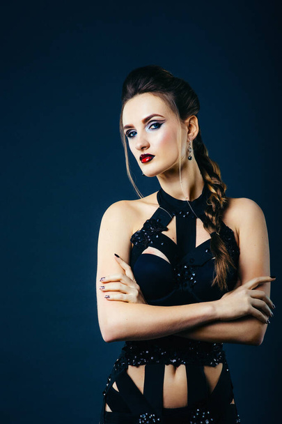 white girl model on a dark background in a dress made of cut stripes of black fabric - Zdjęcie, obraz
