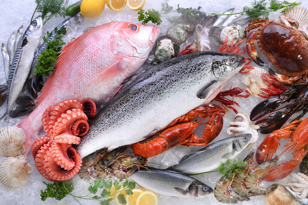 Draufsicht auf die Vielfalt an frischem Fisch und Meeresfrüchten auf Eis mit Trockeneis-Rauch - Foto, Bild