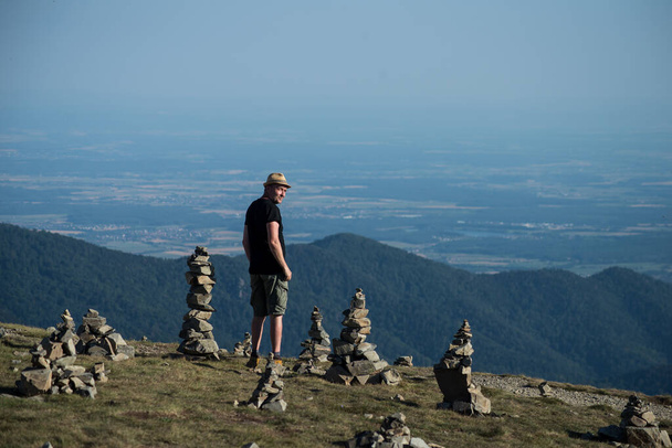 Portrait of man standing at the top of the mountain near  many stones balance on the floor looking the sunset - 写真・画像