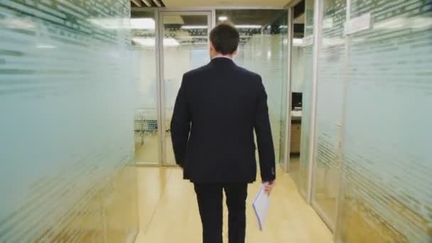 employee walks along brightly lit hallway to workplace - Imágenes, Vídeo