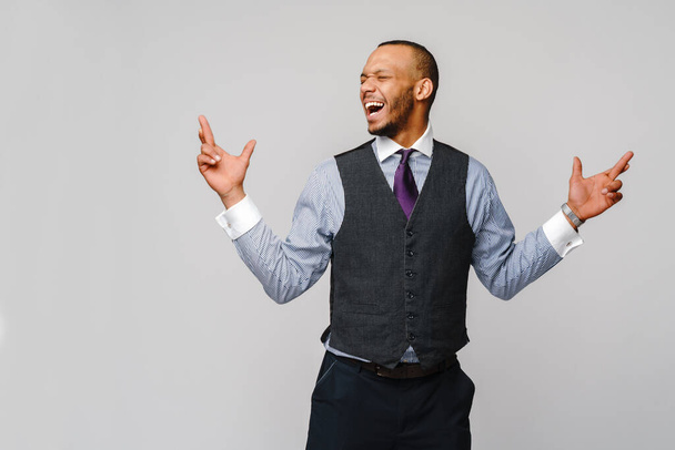 young funny african-american businessman crossing fingers, wishing, hoping for best, miracle over grey background - Foto, immagini