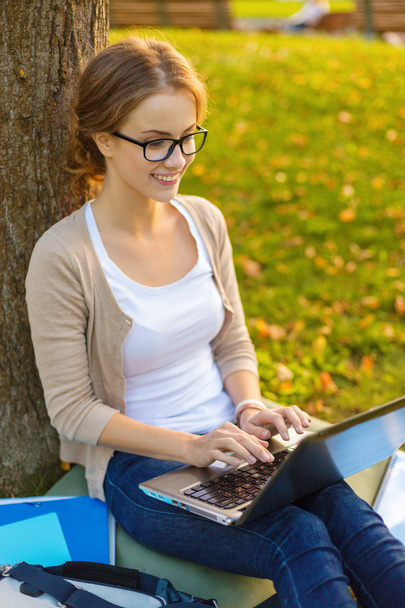 Smiling teenager in eyeglasses with laptop - Fotó, kép