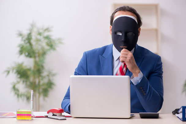Male employee with mask in hipocrisy concept - Photo, Image