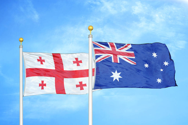Gruzja i Australia dwie flagi na maszcie flagowym i niebieskie zachmurzone tło nieba - Zdjęcie, obraz