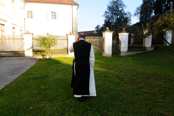 Ordine cistercense, monaco che cammina nel giardino di una comunità di fede cristiana - Foto, immagini