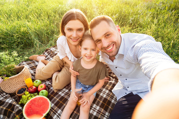 Happy family making selfie sitting in the countryside - Photo, Image