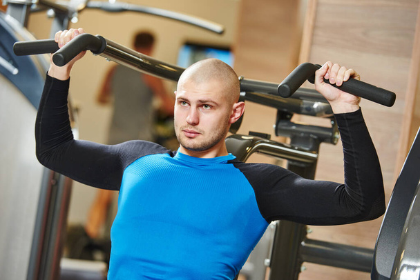 male doing excercise on training machine in gym - Photo, image