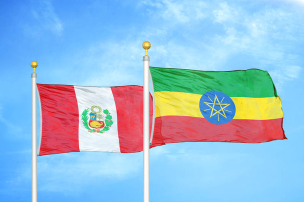 Peru e Etiópia duas bandeiras em postes de bandeira e azul céu nublado fundo
 - Foto, Imagem
