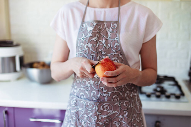 Young woman in the kitchen peels and slices an apple - Foto, Imagen