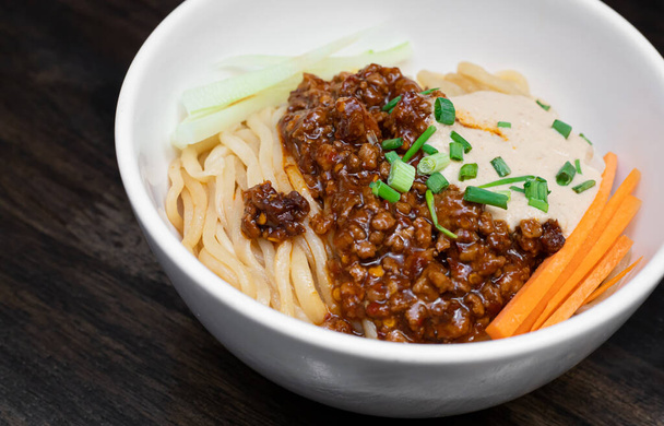 Sichuan Spicy Noodle with garlic chili oil and minced pork, serving on white bowl. Traditional food of Sichuan province. Chinese food concept.  - Photo, Image