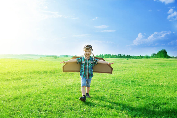 Commencez à voyager dès l'enfance, même dans l'imagination. Rire garçon avec avion sur une pelouse - Photo, image