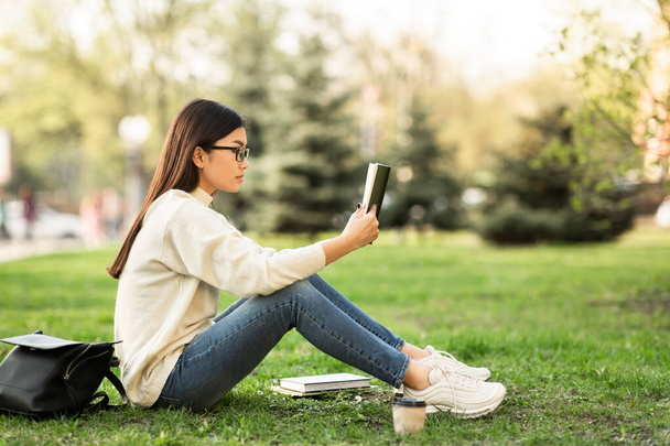 Девушка читает книгу сидя в парке, копирайт - Фото, изображение