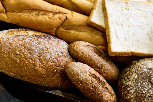 Крупный план ассортимента разновидностей выпеченного коричневого хлеба в деревянном подносе - Фото, изображение