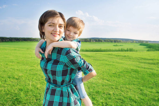 Mother and son having fun on green field - Фото, изображение
