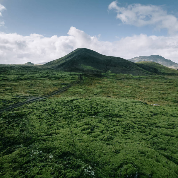 Krajobraz Islandii, widok z lotu ptaka. Wulkaniczne zielone pole lawy mchu i czarna góra z góry - Zdjęcie, obraz