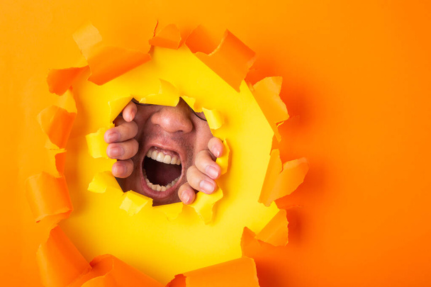 człowiek krzyczy z tyłu dziury pomarańczowy papier - Zdjęcie, obraz