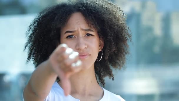Jonge mooie Afro-Amerikaanse vrouw houdt handen uit, geeft duimen neer gebaar van frustratie en walging. Meisje drukt haar ware negatieve emoties uit, kijkt afkeurend, schudt haar hoofd, zegt nee. - Video