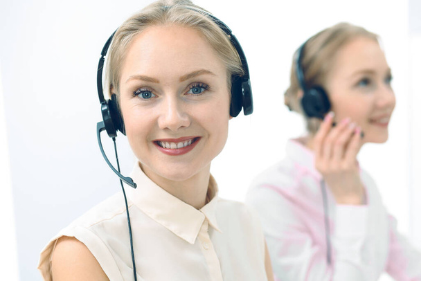 Bright and sunny call center. Group of blonde women in headset at work. Office and business concept - Фото, изображение