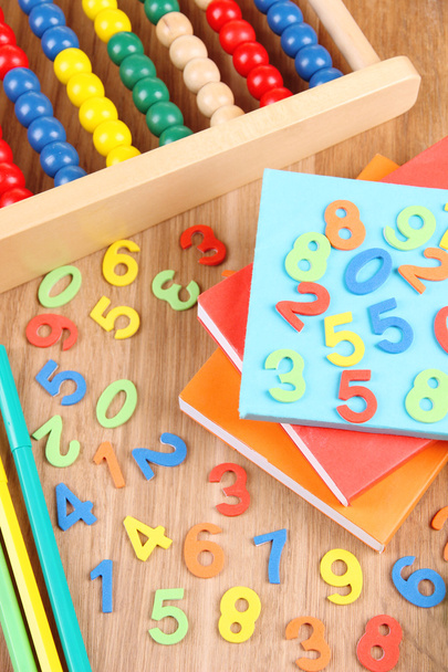 Colorful numbers, abacus, books and markers on wooden background - Photo, image