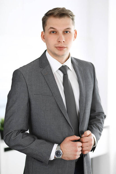Headshot of businessman standing straight with colleagues at background in office. Group of business people discussing questions at conference or presentation. Success and business concept - Photo, image