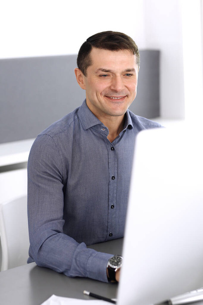 Businessman working with computer in modern office. Headshot of male entrepreneur or company director at workplace. Business concept - Foto, Bild