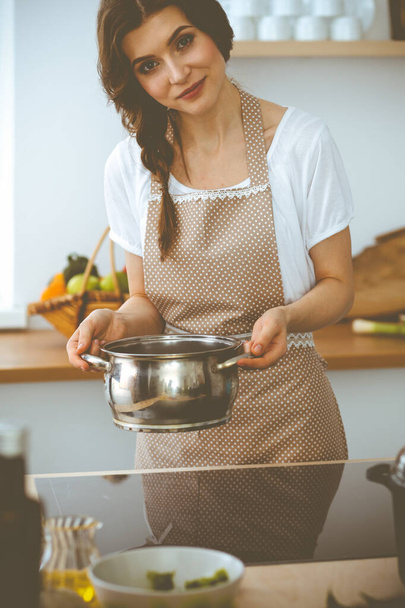 Young brunette woman cooking soup in kitchen. Food and health concept - Foto, immagini