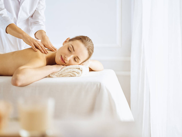 Beautiful woman enjoying back massage with closed eyes. Spa treatment concept - Foto, Imagen