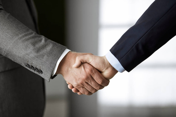 Business people in office suits standing and shaking hands, close-up. Business communication concept. Handshake and marketing - Valokuva, kuva