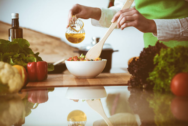 Unknown human hands cooking in kitchen. Woman is busy with vegetable salad. Healthy meal, and vegetarian food concept - Photo, Image