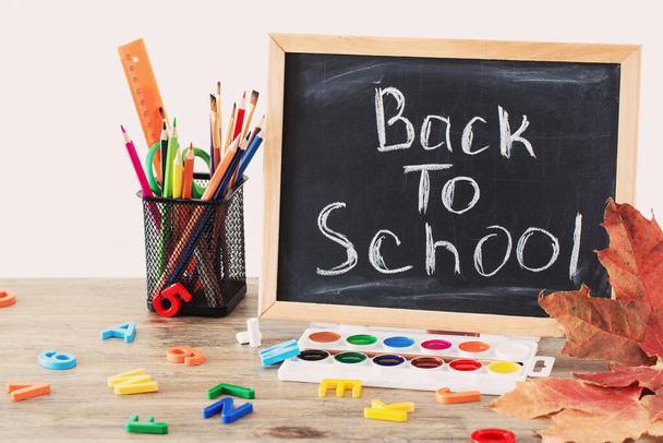 quadro-negro com texto e material escolar em mesa de madeira, de volta ao conceito de escola
 - Foto, Imagem