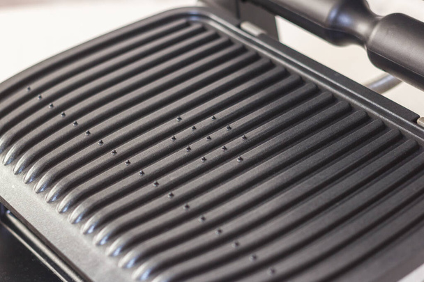 Ridge teflon surface of an electric grill. Close-up view of barbecue for home use. - Фото, изображение