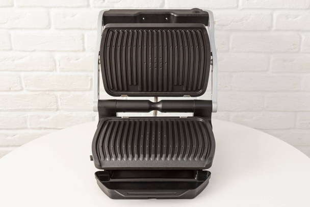 Open empty electric grill. Barbecue for home use on white kitchen background. - Foto, Imagem