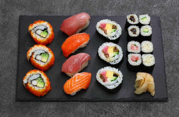 japán sushi válogatott: kaliforniai tekercs, maguro (tonhal), lazac, futomaki (sushi burrito), negitoro (darált tonhal tekercs), takuan (ecetes daikon retek), kanpyo (szárított tök), kappa (uborka), gari (ecetes gyömbér) - Fotó, kép