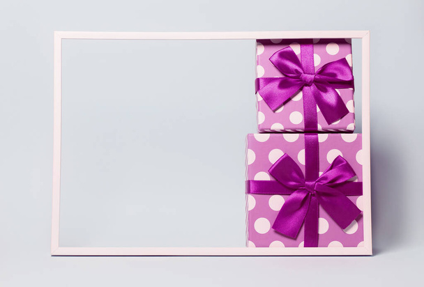 Deux boîtes cadeaux avec des points enveloppés avec un ruban lumineux sur fond coloré. Thème festif et vacances. Cadeau de Noël ou d'anniversaire. Concept de vente et d'achat. - Photo, image