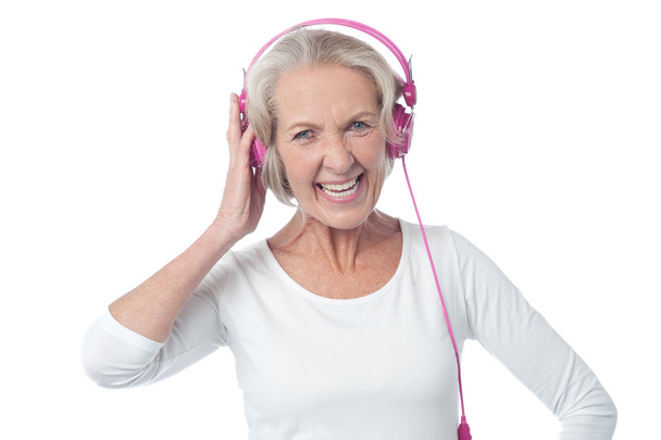 Aged woman listening to music - Foto, afbeelding