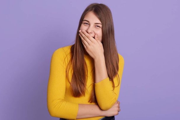 Attractive young woman looks happy and excited, surprised and amazed covering mouth with hands, girl cute expression, posing against lilac background. - 写真・画像
