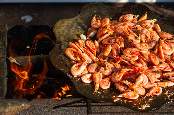 креветки. Креветки готують на сковороді над вогнем. Бонфайрські морепродукти. Продовольча фотографія
 - Фото, зображення