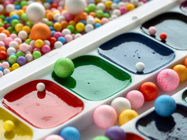 Watercolor paints are arranged diagonally on a background with colorful balls. - Photo, Image