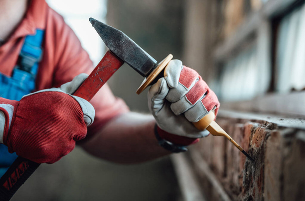 Workers strong hands with hammer and chisel, getting rid of plaster on a brick wall - Zdjęcie, obraz