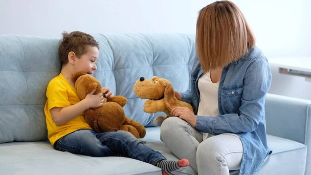 View of mother having fun with baby. mother and son playing with toy on sofa. have fun together. mom is trying to make contact with her hyperactive son - 写真・画像