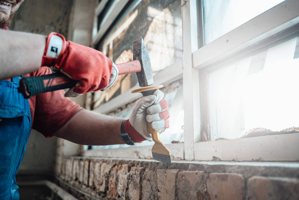 Εργάτες δυνατά χέρια με σφυρί και σμίλη, να απαλλαγούμε από γύψο σε έναν τοίχο από τούβλα - Φωτογραφία, εικόνα